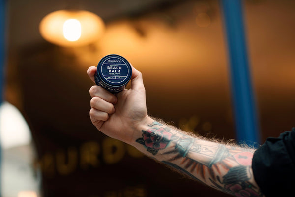 Beard Balm 50ml held by a barber outside our store